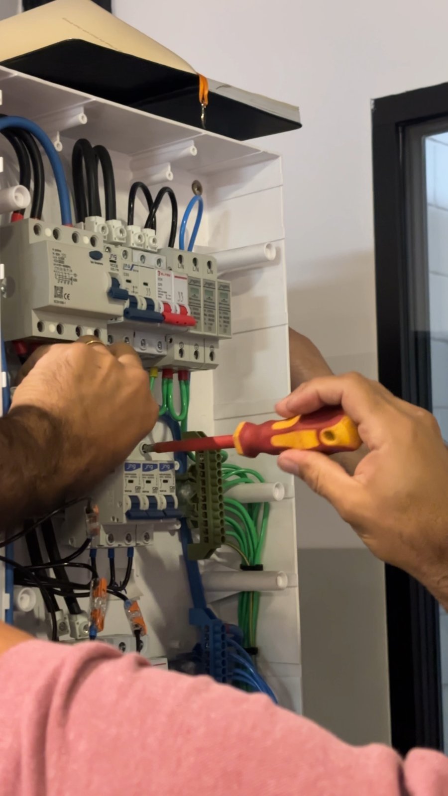 Aluno ligando os cabos de um quadro de energia na bancada