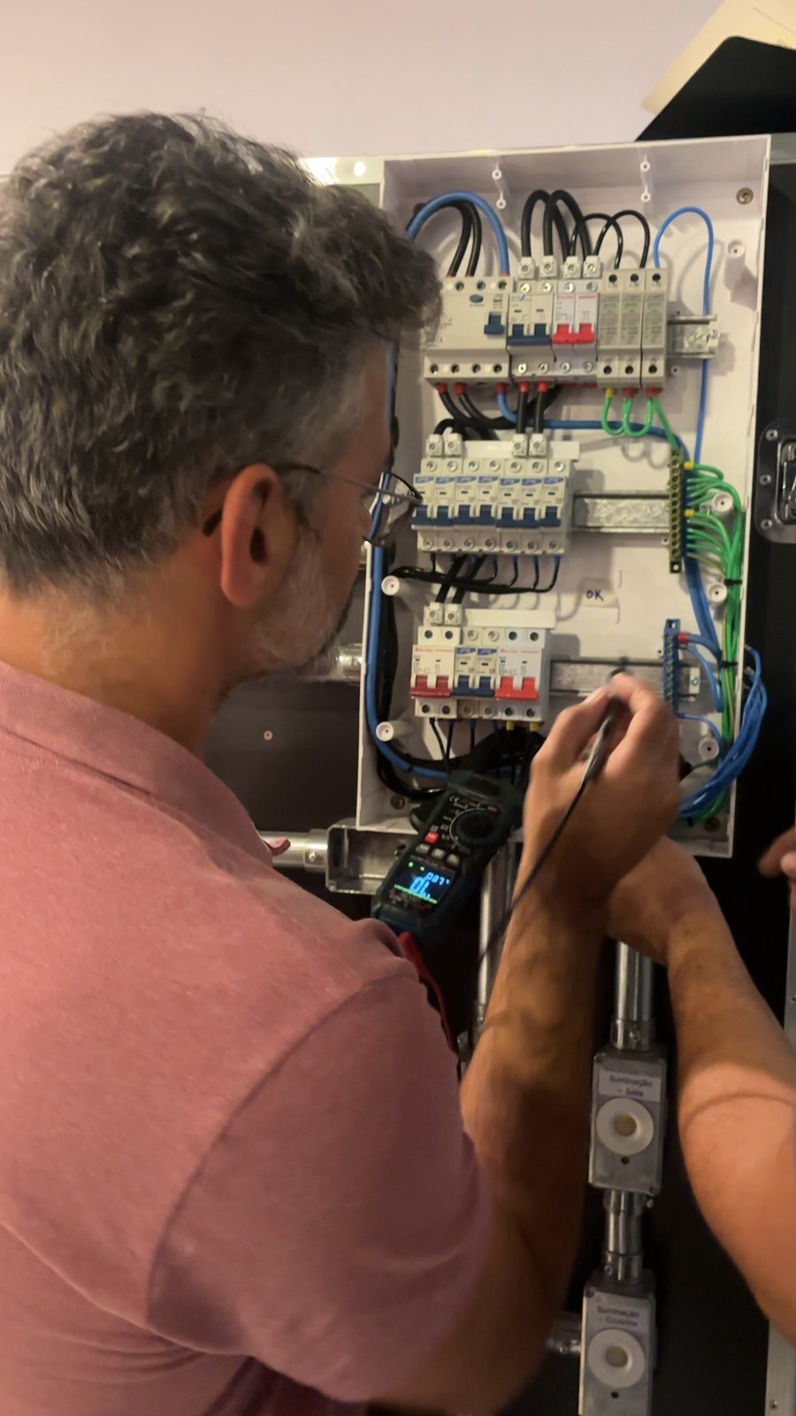 Participante medindo a instalação elétrica com multímetro na bancada